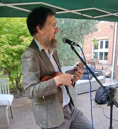 Small picture of Eric playing uke, with seasonal jumper on.