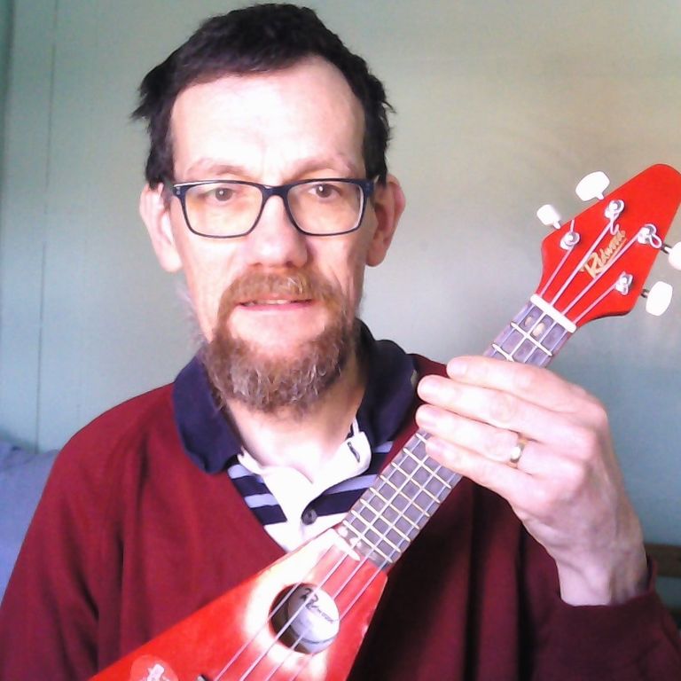 Eric posing with his bright-red 'flying-V' uke