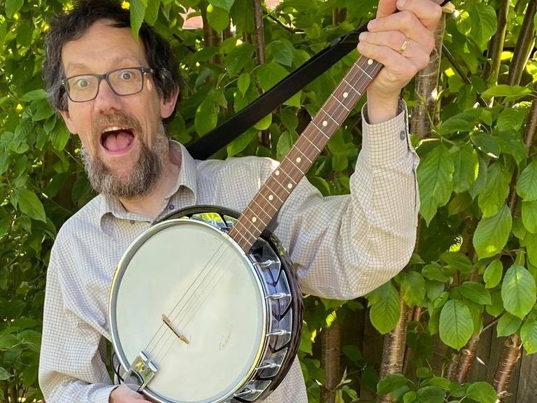 Eric, posing in the garden with his tenor banjo (greenery behind)
