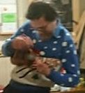 Small picture of Eric playing uke, with seasonal jumper on.